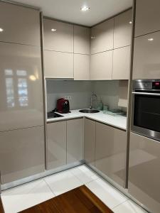 eine Küche mit weißen Schränken, einer Spüle und einer Mikrowelle in der Unterkunft Oporto Chic & Cozy Cardosas in Porto