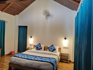 a bedroom with a bed with blue curtains and a fan at LaSerene The Cottage in Nainital