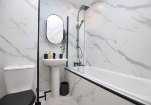 a white bathroom with a sink and a mirror at The Warren Apartment in Greenock
