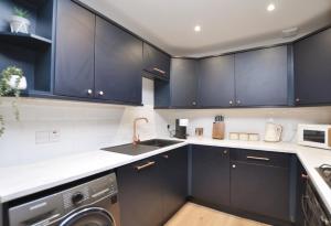 a kitchen with black cabinets and a dishwasher at The Warren Apartment in Greenock