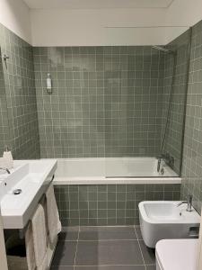 ein Badezimmer mit einer Badewanne, einem WC und einem Waschbecken in der Unterkunft Oporto Chic & Cozy Cardosas in Porto