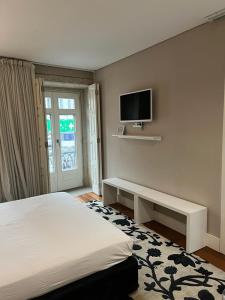 ein Schlafzimmer mit einem Bett und einem TV an der Wand in der Unterkunft Oporto Chic & Cozy Cardosas in Porto
