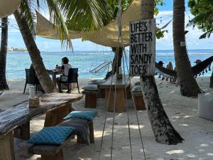 a sign on a beach with tables and chairs at Canopus Retreat Thulusdhoo in Thulusdhoo