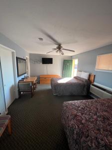 Western Motel في Sayre: غرفة فندقية بسريرين ومروحة سقف