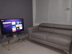 een woonkamer met een bank en een flatscreen-tv bij Piso entero, cómodo y moderno in Mexico-Stad