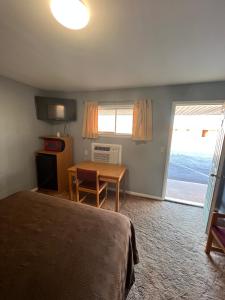 a bedroom with a bed and a table and a window at Western Motel in Sayre