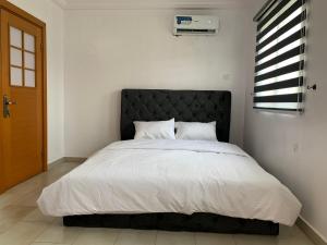 een slaapkamer met een groot bed met een zwart hoofdeinde bij Modern 2BDR APT - Wi-Fi, Kitchenette, Pool & 24hrs Security, Netflix in Ikeja