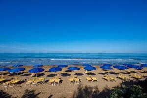 eine Gruppe blauer Sonnenschirme und Stühle am Strand in der Unterkunft Park Hotel I Lecci in San Vincenzo