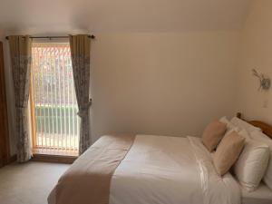 a bedroom with a white bed and a window at Meals Farm Holiday Cottages - The Stables in North Somercotes