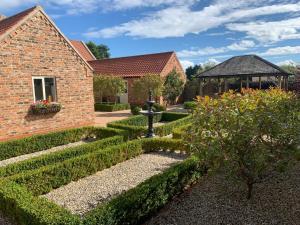 um jardim com uma fonte e um edifício de tijolos em Meals Farm Holiday Cottages - The Stables em North Somercotes