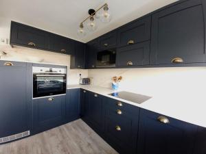 eine Küche mit marineblauen Schränken und einem Waschbecken in der Unterkunft Sea View 3 bedroom seaside property in Chichester