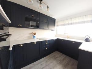 eine Küche mit schwarzen Schränken und weißen Arbeitsplatten in der Unterkunft Sea View 3 bedroom seaside property in Chichester