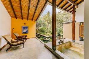 Aditya Resort في هيكادوا: غرفة معيشة مفتوحة مع نافذة كبيرة وحوض استحمام