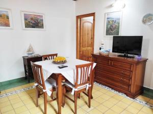 een eetkamer met een witte tafel en een televisie bij Casa Lupino in Orosei