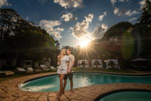 a man and a woman standing next to a swimming pool at Altenhaus Pousada Itaipava in Itaipava