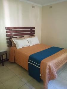 um quarto com uma cama grande e uma cabeceira em madeira em 2 bed guesthouse in Mabelreign - 2012 em Harare