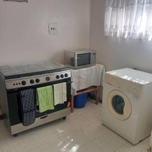 a kitchen with a stove and a microwave and a washing machine at 2 bed guesthouse in Mabelreign - 2012 in Harare