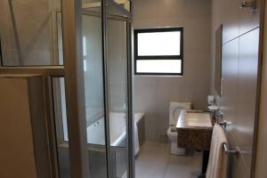 a bathroom with a shower and a toilet and a sink at A pristine BB located in Belvedere Harare - 2010 in Harare