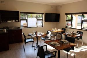 a dining room with tables and chairs and windows at A pristine BB located in Belvedere Harare - 2010 in Harare