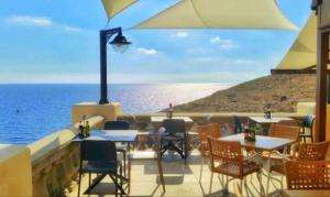 un restaurante con mesas y sillas y vistas al océano en Stylish 3Bed Penthouse close to the Blue Grotto en Żurrieq