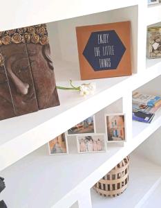 a shelf with pictures and a sign that reads enjoy the little things at Stylish 3Bed Penthouse close to the Blue Grotto in Żurrieq