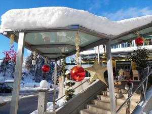 une véranda couverte de décorations de Noël dans la neige dans l'établissement Gasthof Klug zum Ehrensepp, à Modriach