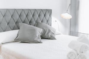 un lit blanc avec deux oreillers et une tête de lit dans l'établissement Expoholidays - Primera línea de playa Villapepita PARKING gratis, à Almería