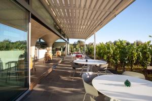 an outdoor patio with tables and chairs and windows at Tenuta di Castellaro Winery & Resort in Lipari