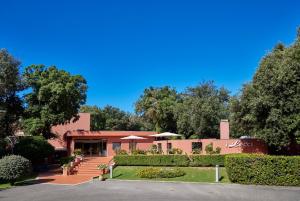 a building with a patio and trees in the background at Park Hotel I Lecci in San Vincenzo