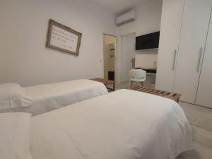 a white bedroom with two beds and a kitchen at fuORIOrbita in Orio al Serio