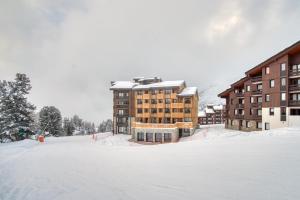 un aparcamiento cubierto de nieve frente a un edificio en Chalet Hôtel Turquoise, en La Plagne Tarentaise