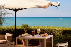 a table with food and drinks and an umbrella at Park Hotel I Lecci in San Vincenzo