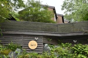 uma casa com uma placa ao lado de uma cerca em guest house windy em Yamanakako