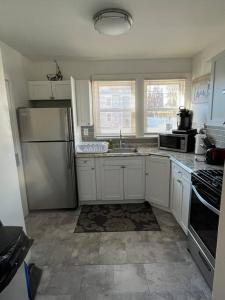 a kitchen with white cabinets and a stainless steel refrigerator at Three Bed One Bath Apt 25 mins to NYC in Belleville