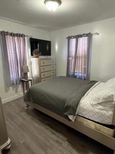 Schlafzimmer mit einem Bett, einer Kommode und Fenstern in der Unterkunft Three Bed One Bath Apt 25 mins to NYC in Belleville