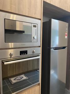a kitchen with a stainless steel oven and a refrigerator at Mawar Villa By Malvacae Homestay Shah Alam in Shah Alam