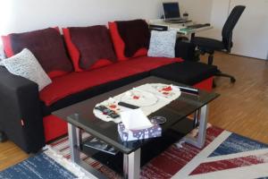 a living room with a red couch and a table at 1 apartment with 2rooms in München in Munich