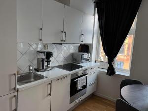a kitchen with white cabinets and a sink and a window at Fløyen Apartment in Bergen