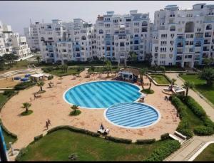 ein großer Pool vor einem großen Gebäude in der Unterkunft Cité Jardin - Appartement Martil avec Climatisation in Martil