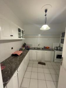 eine Küche mit weißen Schränken und einer schwarzen Arbeitsplatte in der Unterkunft Cité Jardin - Appartement Martil avec Climatisation in Martil