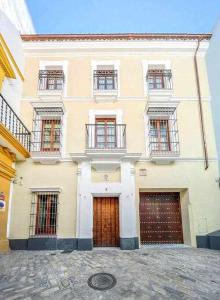 un grand bâtiment blanc avec deux portes de garage dans l'établissement Judería de Sevilla V Luxury Apartments, à Séville