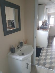 a white bathroom with a sink and a mirror at Lovely 2-Bed Chalet at Robinhood Retreat Free park in Nottingham