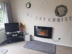 a living room with a fireplace and a happy christmas sign at Lovely 2-Bed Chalet at Robinhood Retreat Free park in Nottingham