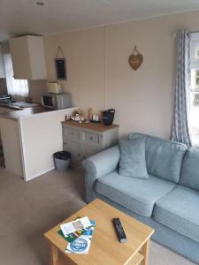 a living room with a blue couch and a table at Lovely 2-Bed Chalet at Robinhood Retreat Free park in Nottingham