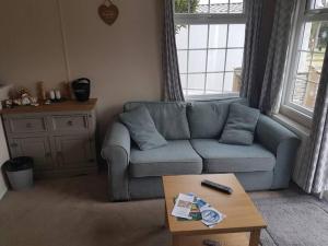 a living room with a blue couch and a coffee table at Lovely 2-Bed Chalet at Robinhood Retreat Free park in Nottingham
