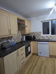 a kitchen with wooden cabinets and a counter top at Greatmindz's home away from home in Bloxwich