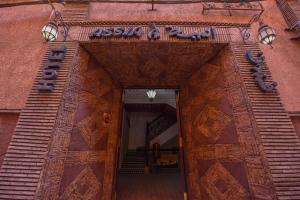 une porte d'entrée menant à un bâtiment avec un panneau sur celui-ci dans l'établissement Riad Assia, à Marrakech