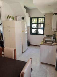 a kitchen with a white refrigerator and a table at Castillo del Lago Carlos Paz - Solo Familiar in Villa Carlos Paz