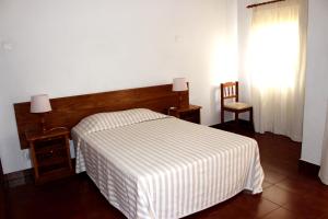 a bedroom with a bed and a window and a chair at Clube Alvorférias in Alvor