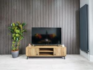 TV de pantalla plana en la parte superior de un centro de entretenimiento de madera en Modern apartment near Wembley Stadium en Londres
